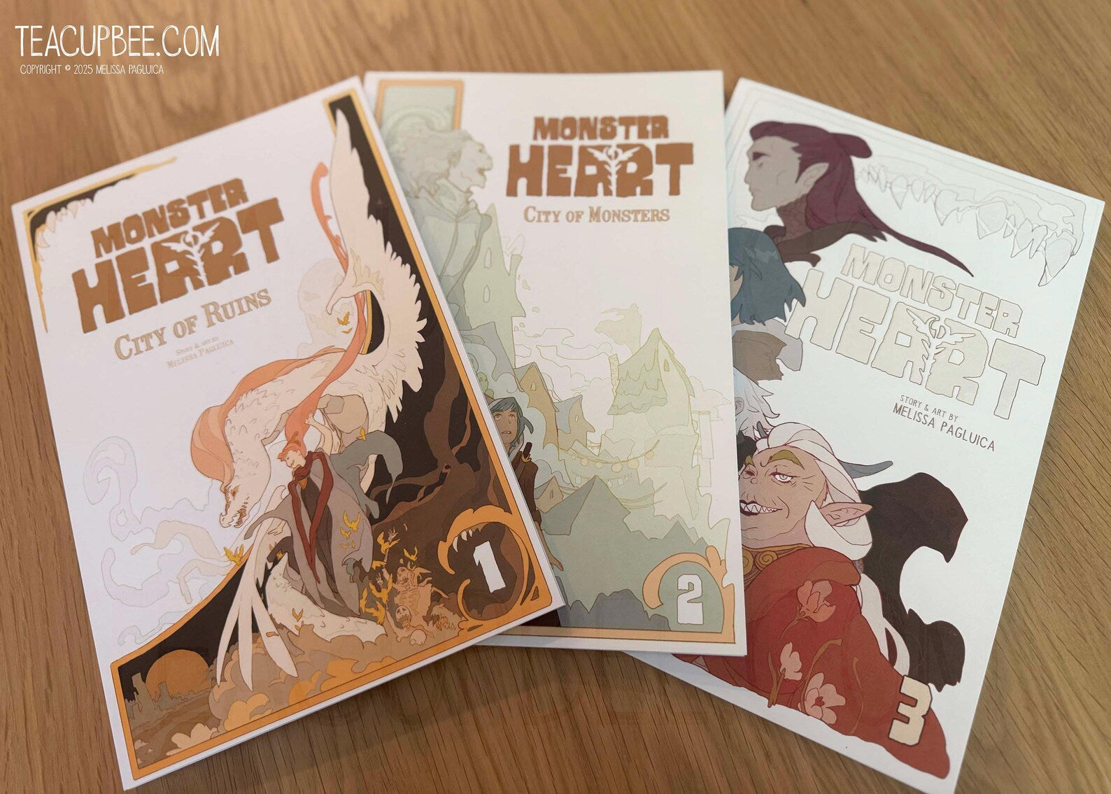 Three comic book covers titled 'Monster Heart' on a wooden surface