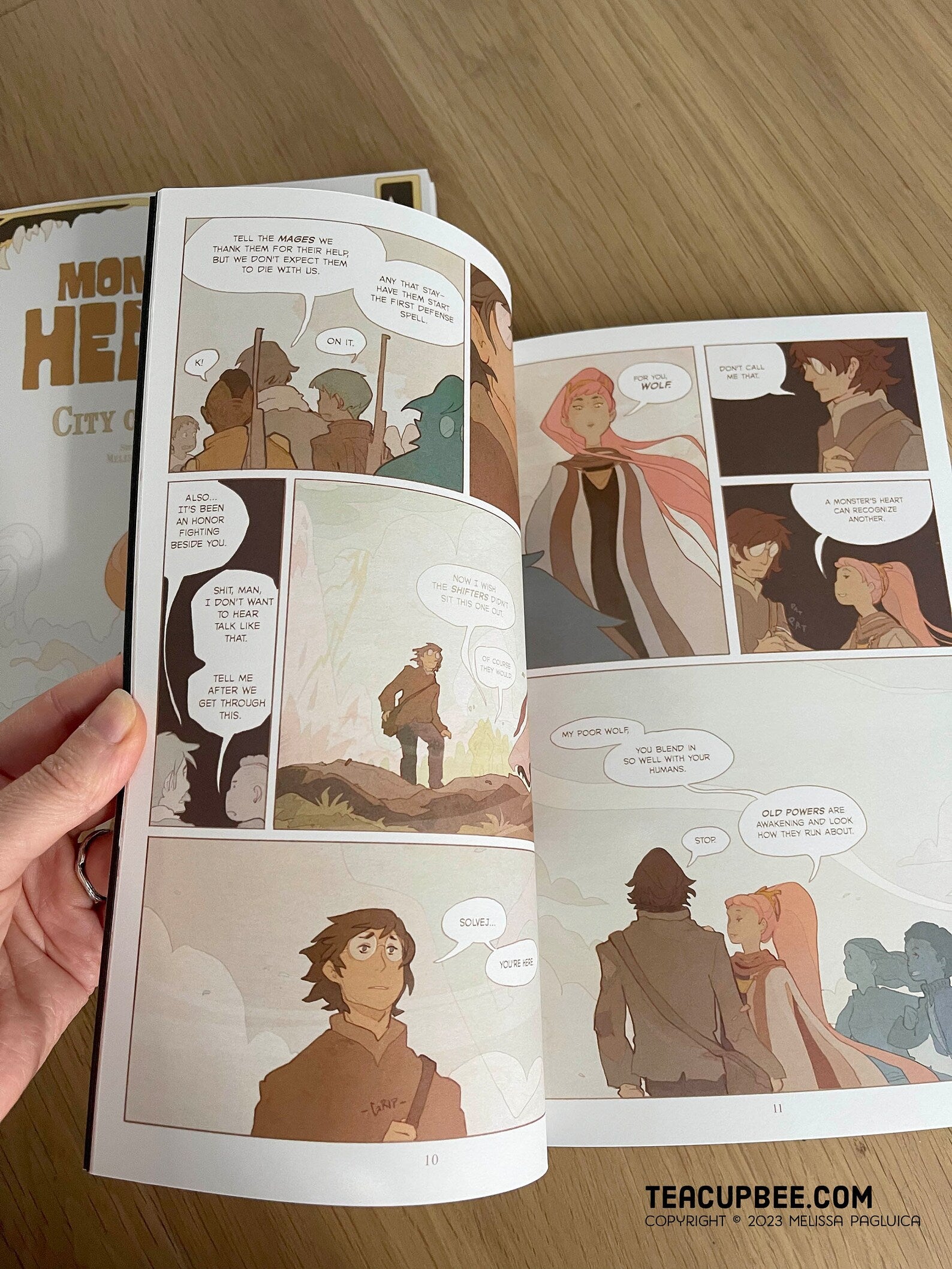 Comic book open to a page with character illustrations and dialogue bubbles.