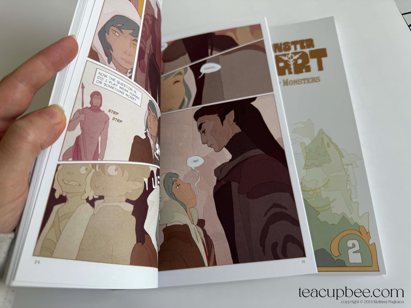 Comic book open to a page with illustrations and text, held by a hand.