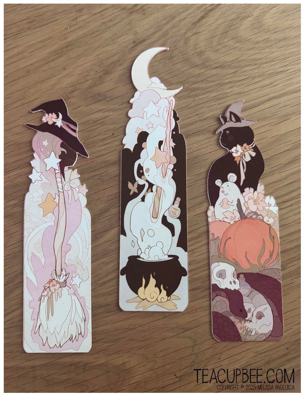 Three decorative bookmarks with witch-themed illustrations on a wooden surface.