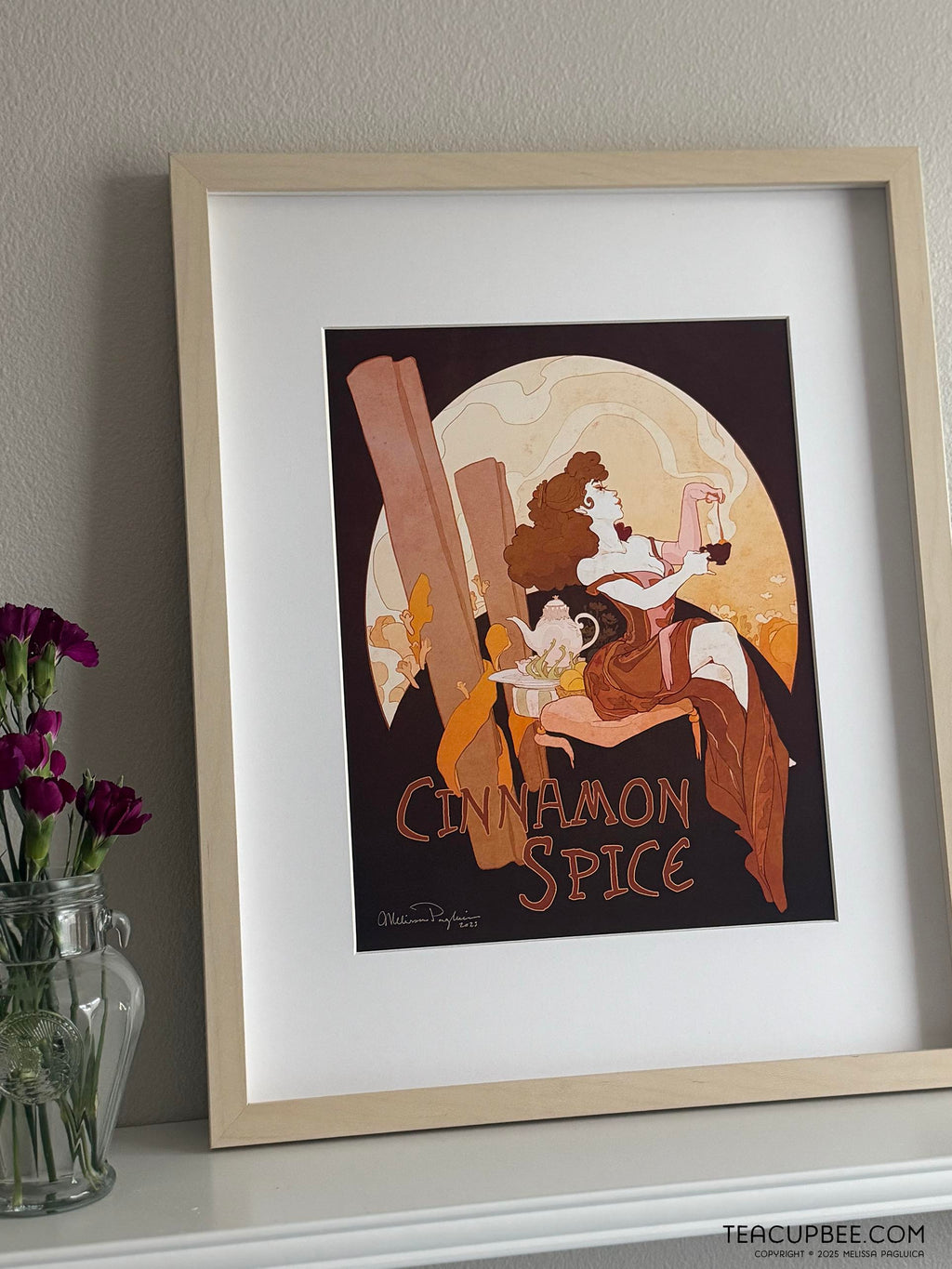 Framed artwork titled 'Cinnamon Spice' on a shelf with a vase of flowers.