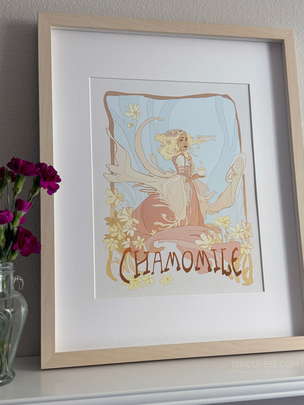 Framed artwork with a fairy and floral design, labeled 'Chamomile', on a shelf with flowers.