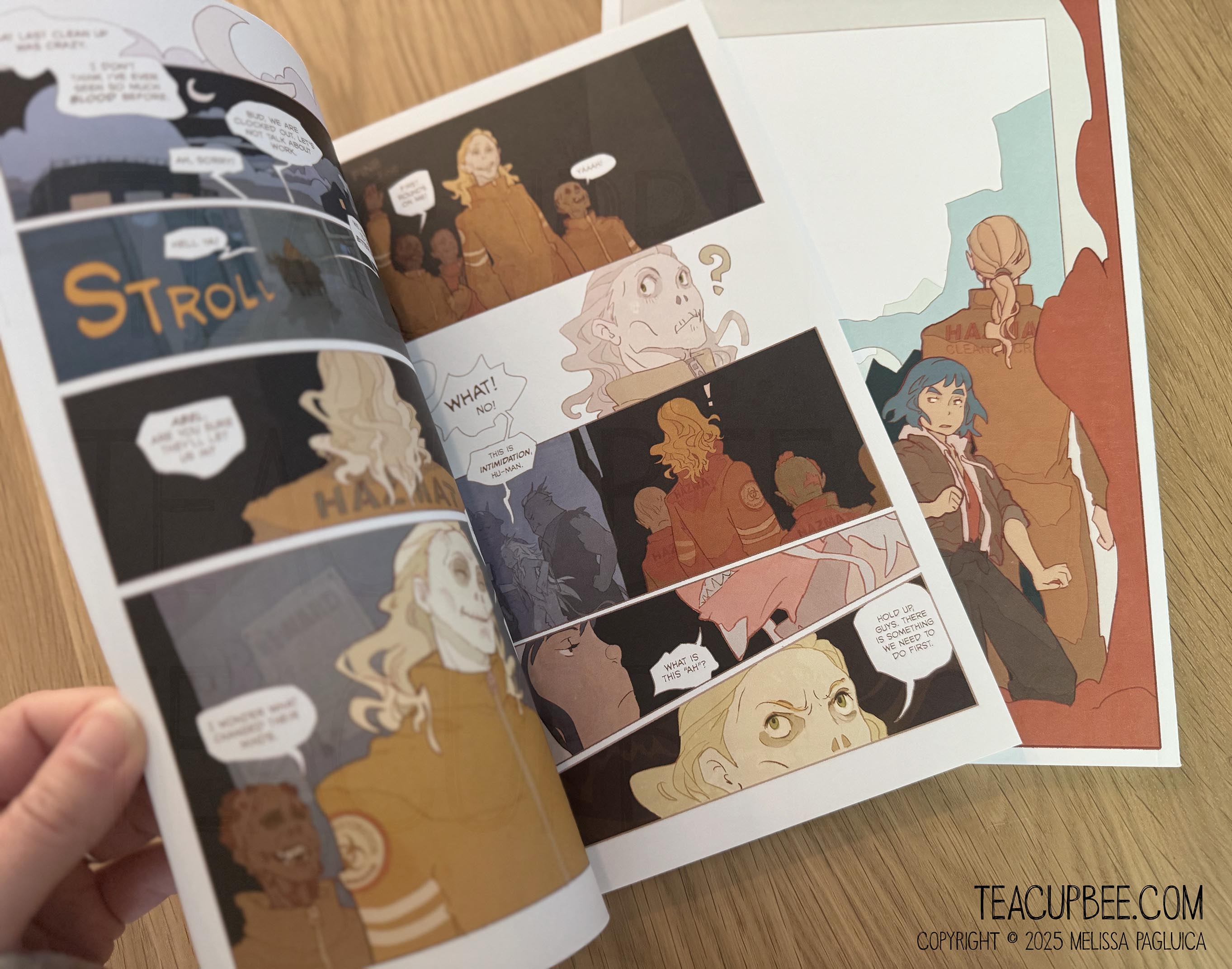 Comic book open to a page with character illustrations on a wooden surface