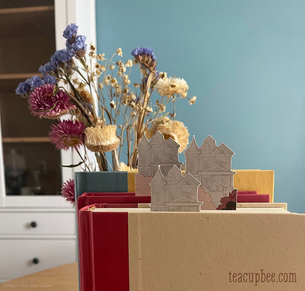 Decorative setup with small houses, flowers, and books on a surface.