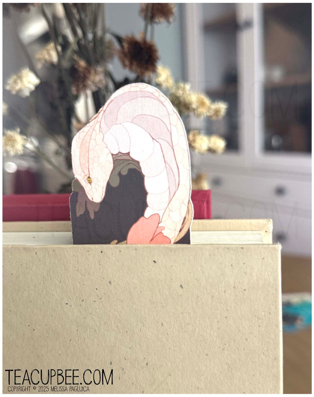 Decorative bookmark with a snake design sitting inside a book, blurred background