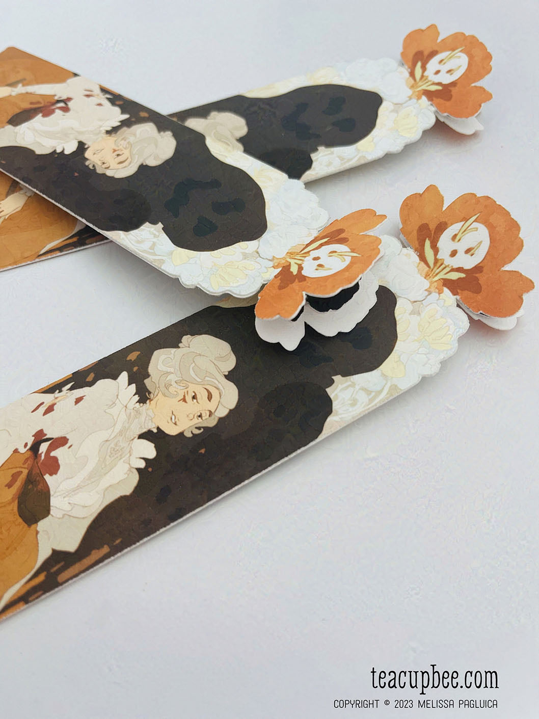 Decorative paper bookmarks with floral and skull designs on a white background